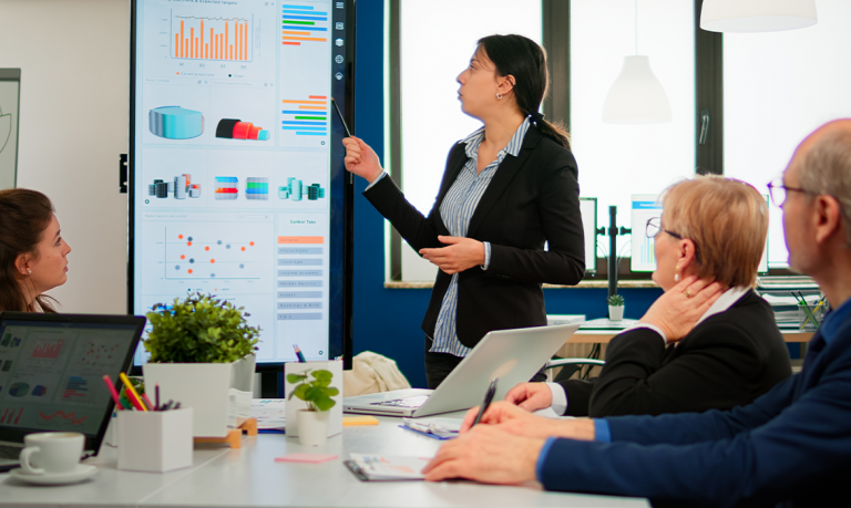 Riunione in ufficio con donna che illustra una ricerca con grafici